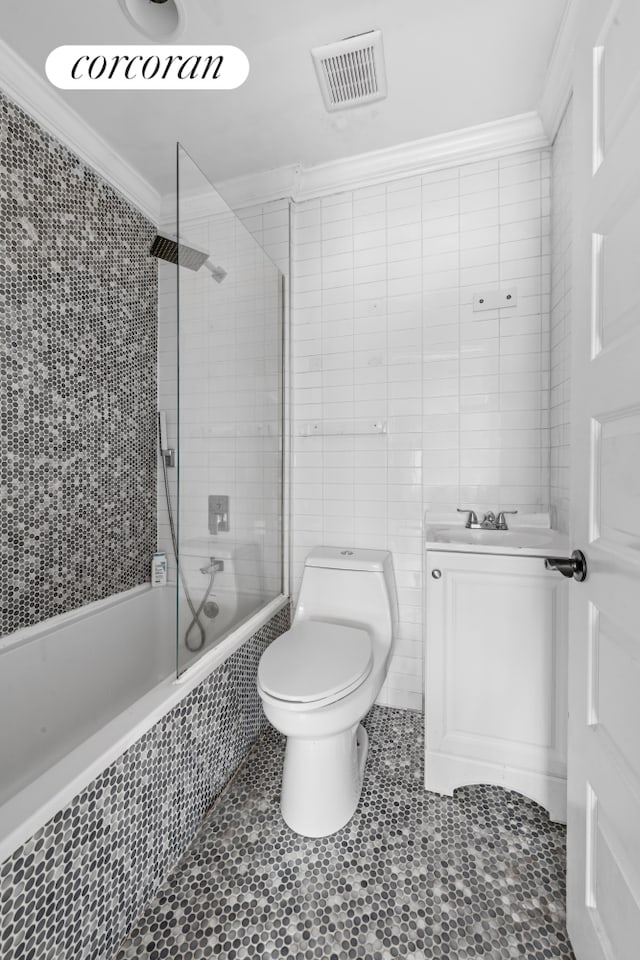 full bathroom featuring tiled shower / bath, vanity, ornamental molding, tile walls, and toilet