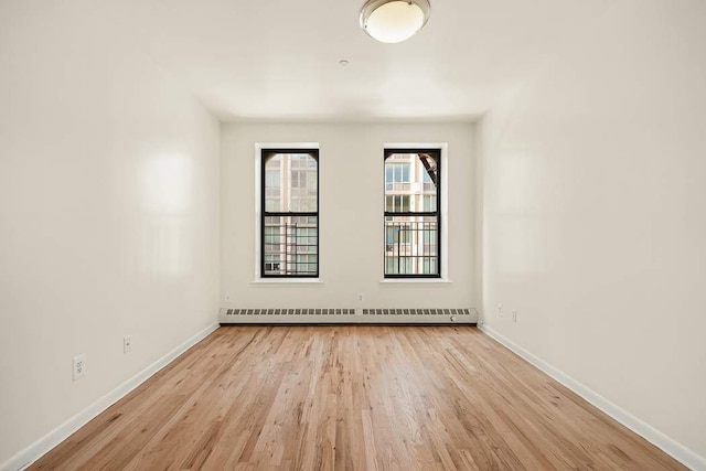 unfurnished room with baseboard heating and light hardwood / wood-style floors