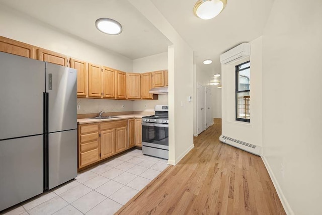 kitchen with appliances with stainless steel finishes, sink, light brown cabinetry, a wall mounted AC, and light hardwood / wood-style flooring