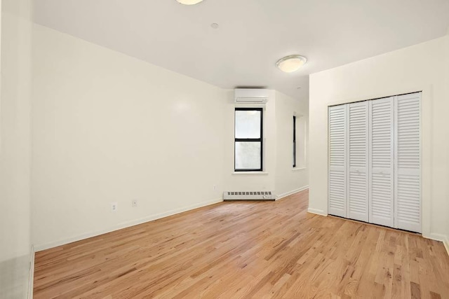 unfurnished bedroom with a wall mounted AC, light hardwood / wood-style flooring, and a closet