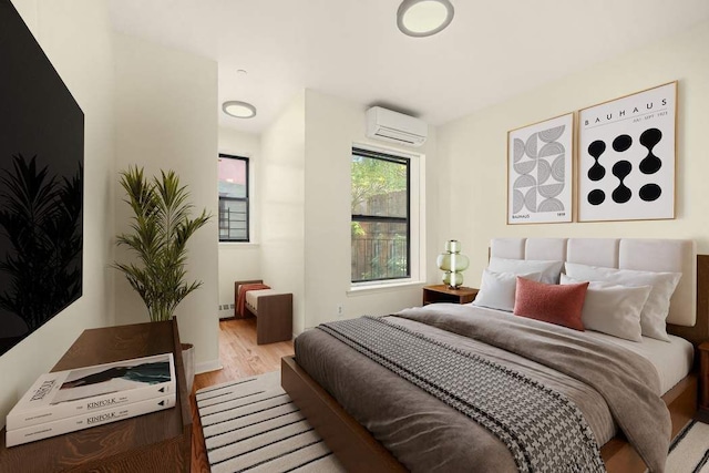 bedroom with hardwood / wood-style floors and a wall unit AC