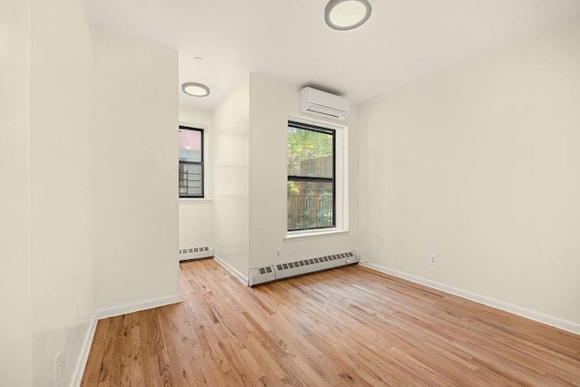 empty room with a wall mounted AC, a baseboard radiator, and light hardwood / wood-style flooring