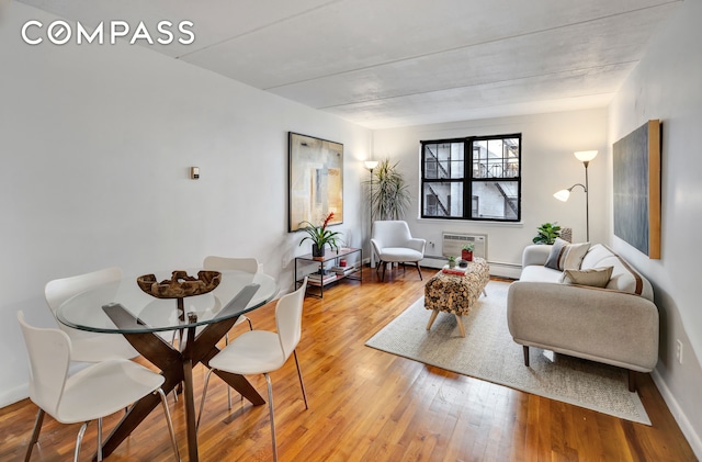 living room with light hardwood / wood-style floors, a baseboard radiator, and a wall mounted air conditioner