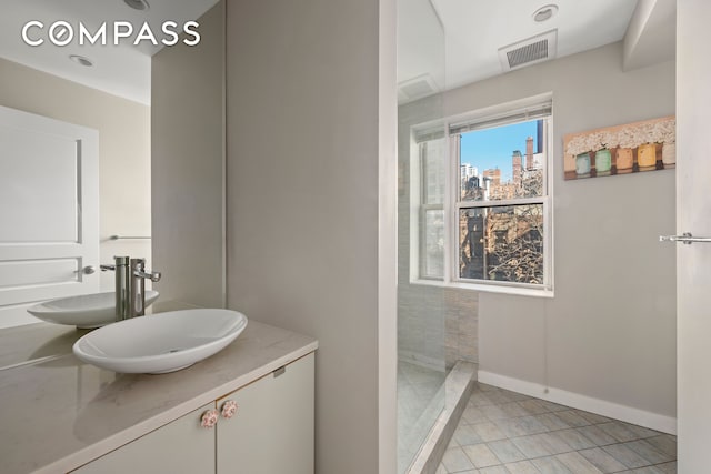 bathroom with vanity, a tile shower, and tile patterned floors