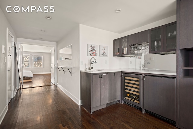 bar featuring stainless steel fridge, dark brown cabinets, beverage cooler, dark wood-type flooring, and sink