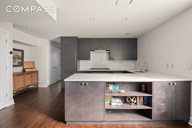 kitchen with kitchen peninsula, sink, dark hardwood / wood-style flooring, stainless steel gas stovetop, and tasteful backsplash