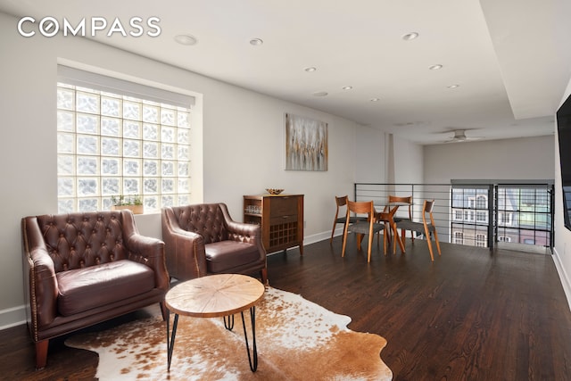 living room featuring dark wood-type flooring, ceiling fan, and plenty of natural light