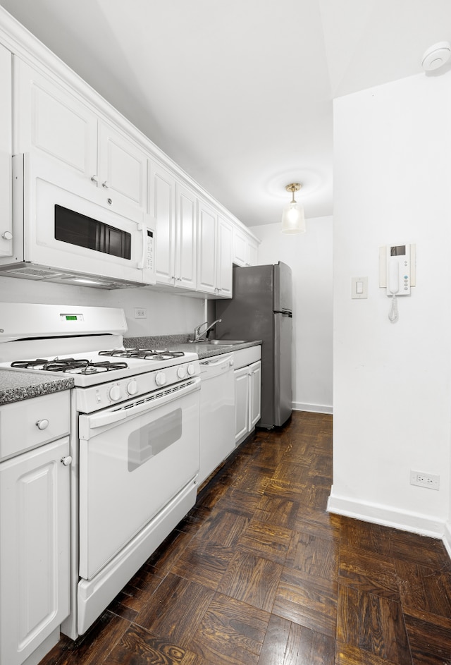 kitchen with white cabinetry, dark parquet floors, sink, and white appliances