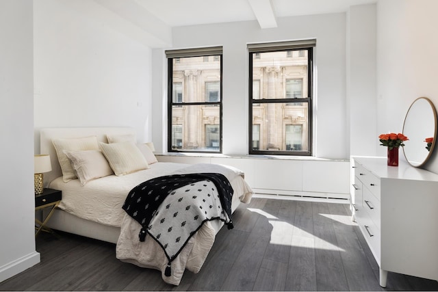 bedroom featuring dark wood-type flooring and beam ceiling