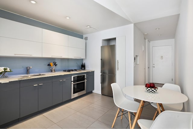 kitchen featuring gray cabinetry, stainless steel appliances, sink, light tile patterned floors, and white cabinets