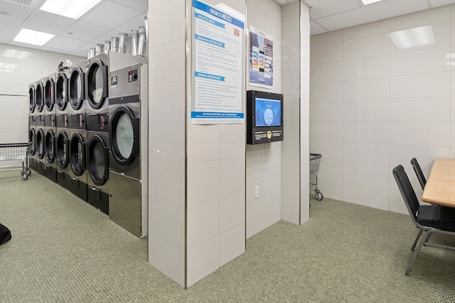 interior space featuring tile walls, stacked washer and clothes dryer, and washing machine and clothes dryer