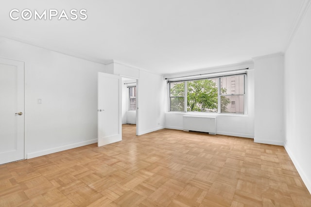 empty room featuring light parquet floors, crown molding, and radiator heating unit