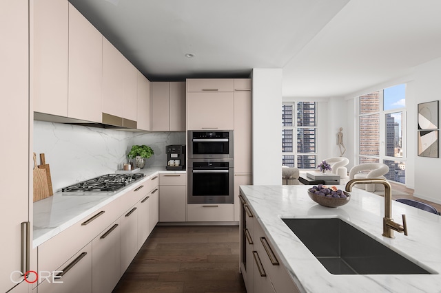 kitchen featuring light stone counters, decorative backsplash, stainless steel appliances, dark wood-type flooring, and sink