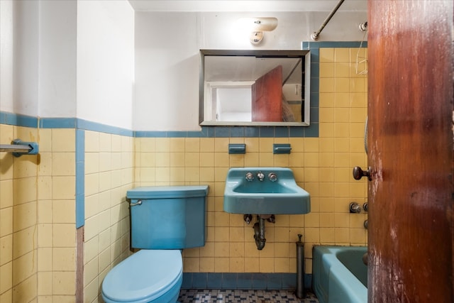 bathroom with sink, toilet, and tile walls