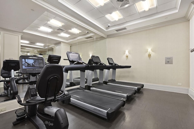 gym with ornamental molding and a tray ceiling