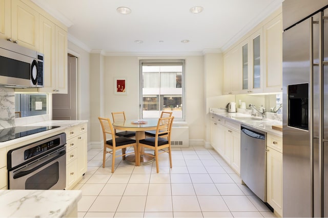 kitchen with light stone counters, light tile patterned flooring, sink, appliances with stainless steel finishes, and crown molding