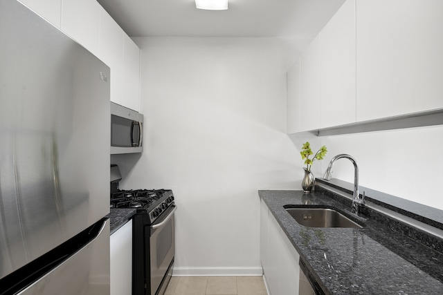 kitchen featuring appliances with stainless steel finishes, white cabinetry, dark stone counters, and sink