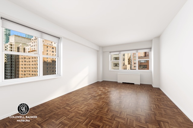 spare room featuring radiator and dark parquet floors