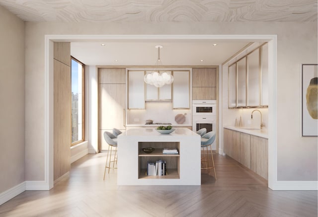 kitchen featuring a breakfast bar, light brown cabinets, and hanging light fixtures