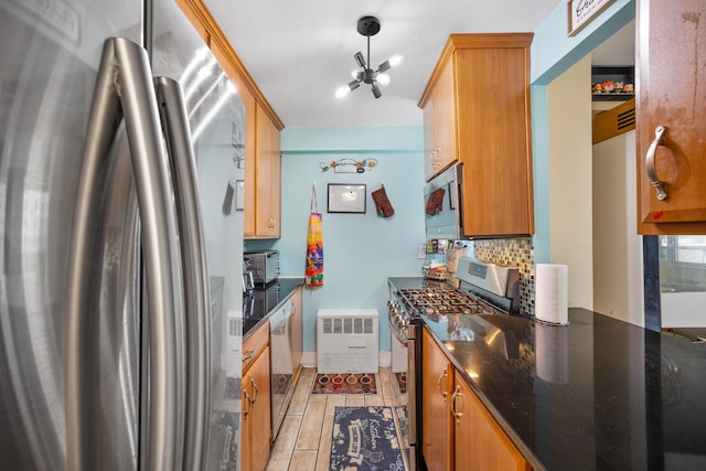 kitchen with a chandelier, appliances with stainless steel finishes, decorative backsplash, and dark stone counters