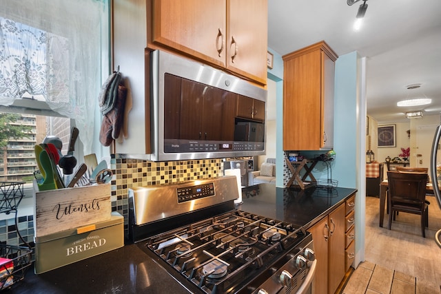 kitchen featuring backsplash, stainless steel appliances, and dark stone counters