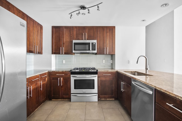 kitchen featuring light stone counters, light tile patterned floors, sink, backsplash, and appliances with stainless steel finishes