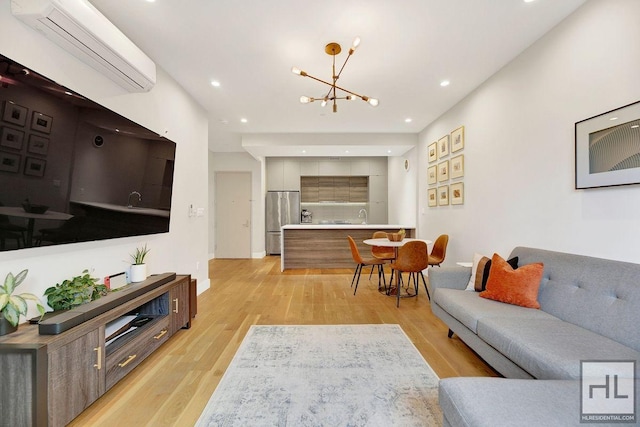 living room featuring light wood-type flooring, an AC wall unit, sink, and an inviting chandelier