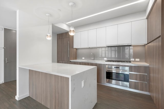 kitchen with white cabinets, backsplash, appliances with stainless steel finishes, dark hardwood / wood-style floors, and pendant lighting