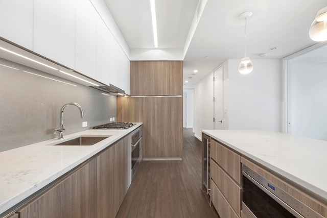 kitchen with dark wood-type flooring, stainless steel appliances, sink, pendant lighting, and white cabinets