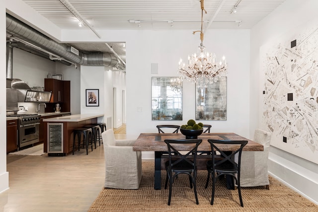 dining space featuring track lighting, wine cooler, sink, light wood-type flooring, and a chandelier