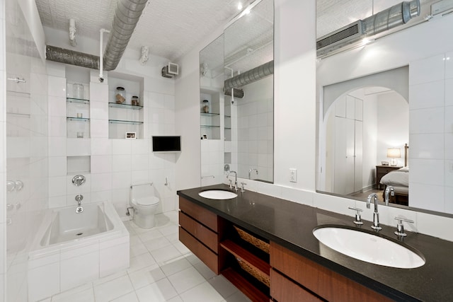 bathroom with tile walls, toilet, a relaxing tiled tub, vanity, and tile patterned floors