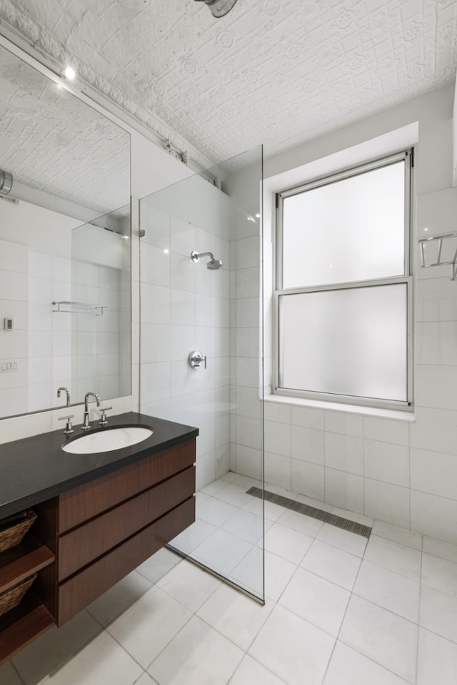 bathroom with vanity, tile patterned floors, tile walls, and tiled shower