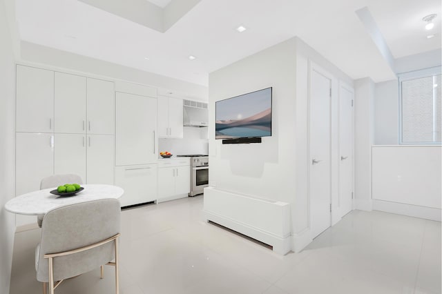 kitchen with exhaust hood, white cabinetry, stainless steel range oven, and light tile patterned flooring