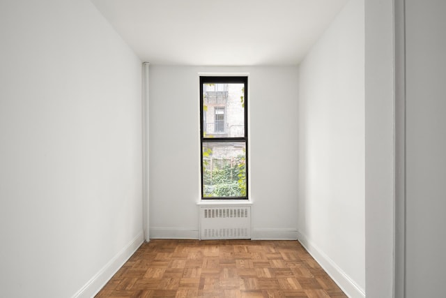 unfurnished room featuring radiator heating unit and light parquet flooring