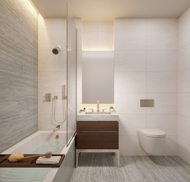 full bathroom featuring vanity, tiled shower / bath, toilet, and tile walls