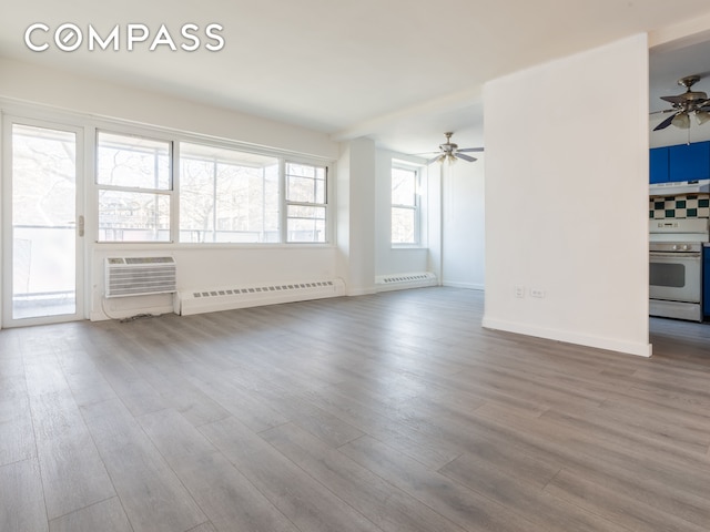 unfurnished living room with baseboard heating, ceiling fan, light wood-type flooring, and plenty of natural light