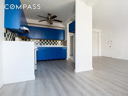 kitchen with blue cabinetry, tasteful backsplash, ceiling fan, and light hardwood / wood-style floors