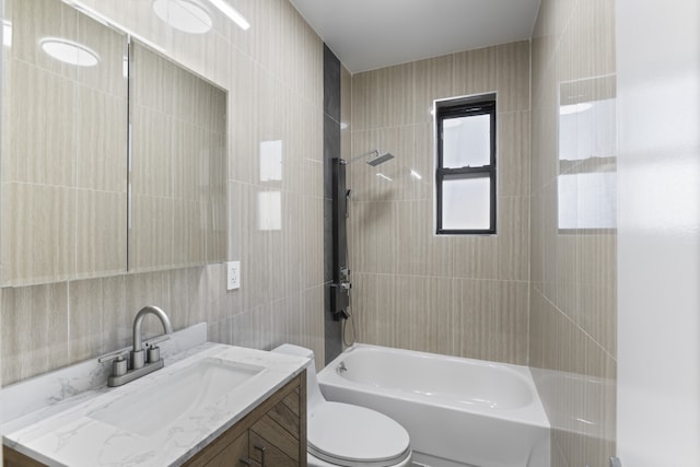 full bathroom featuring tile walls, vanity, tiled shower / bath combo, and toilet