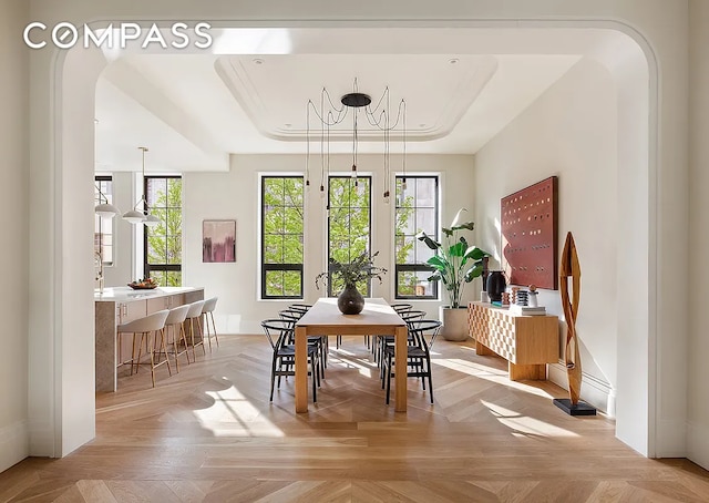 dining space with light parquet floors, a tray ceiling, and a chandelier