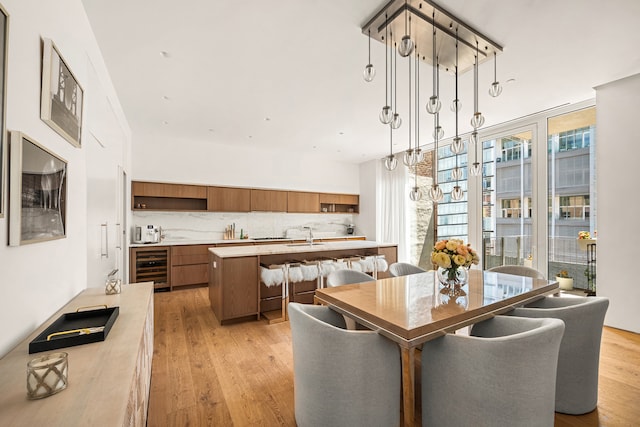 dining area with wine cooler, sink, and light hardwood / wood-style flooring