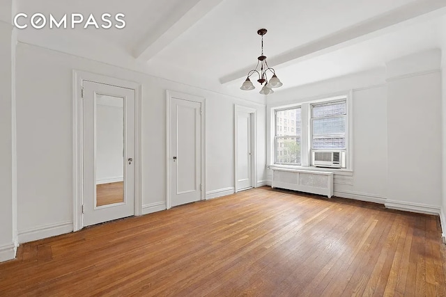 unfurnished bedroom with light hardwood / wood-style floors, radiator heating unit, a chandelier, and two closets