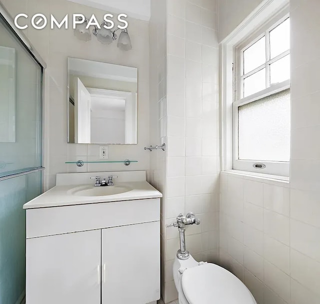 bathroom featuring vanity, toilet, and tile walls