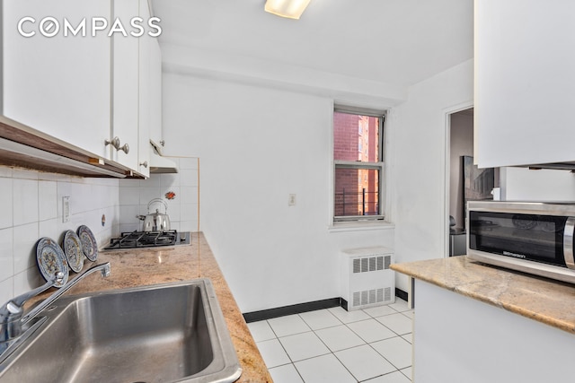 kitchen with white cabinets, backsplash, radiator, stainless steel appliances, and sink