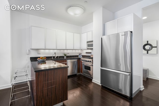 kitchen with sink, dark brown cabinets, dark hardwood / wood-style flooring, white cabinetry, and stainless steel appliances