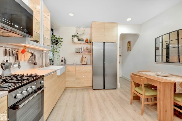 kitchen with light brown cabinets, sink, light wood-type flooring, and stainless steel appliances