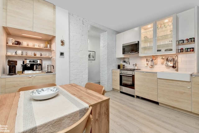 kitchen with backsplash, stainless steel appliances, light hardwood / wood-style flooring, and sink