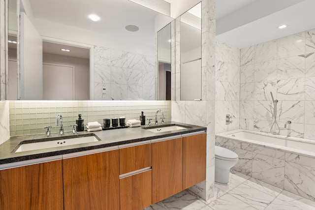 bathroom featuring tile walls, vanity, a relaxing tiled tub, and toilet