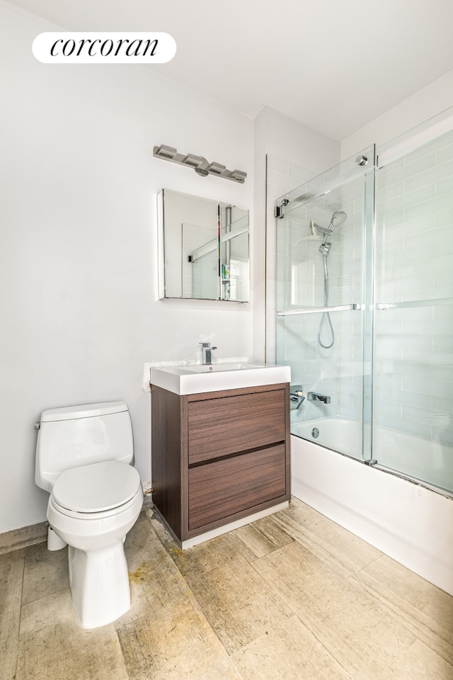 full bathroom featuring hardwood / wood-style floors, vanity, toilet, and shower / bath combination with glass door