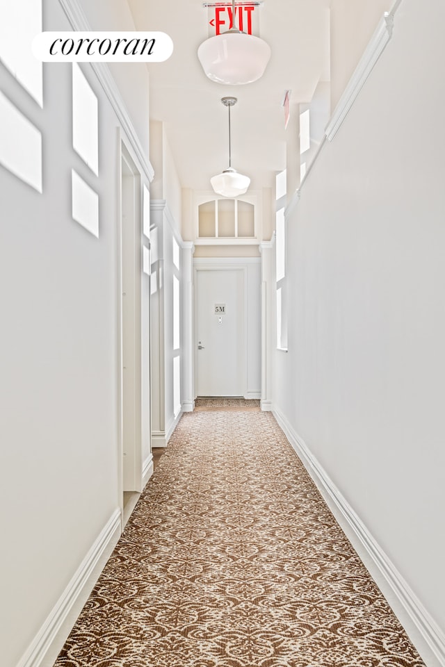 hallway with carpet flooring and a towering ceiling