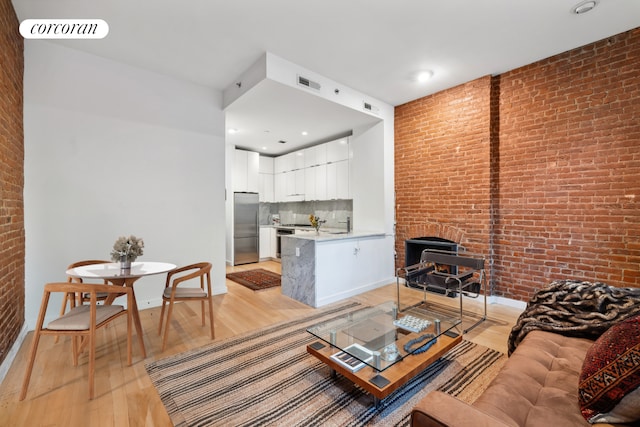 living room with light hardwood / wood-style flooring and brick wall